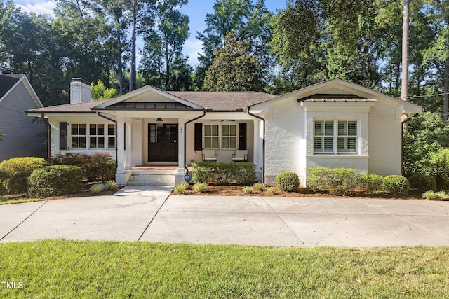 227 W Drewry Ln, Raleigh, NC 27609 - view of front of house featuring a porch, a chimney, and brick siding