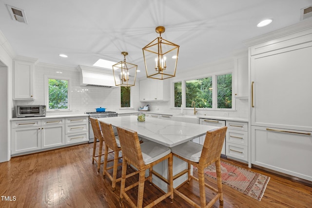 227 W Drewry Ln, Raleigh, NC 27609 - kitchen featuring stainless steel range, backsplash, white cabinets, premium range hood, and a kitchen breakfast bar