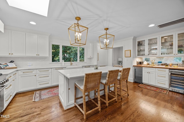 227 W Drewry Ln, Raleigh, NC 27609 - kitchen featuring beverage cooler, white cabinets, decorative backsplash, light wood-type flooring, and recessed lighting