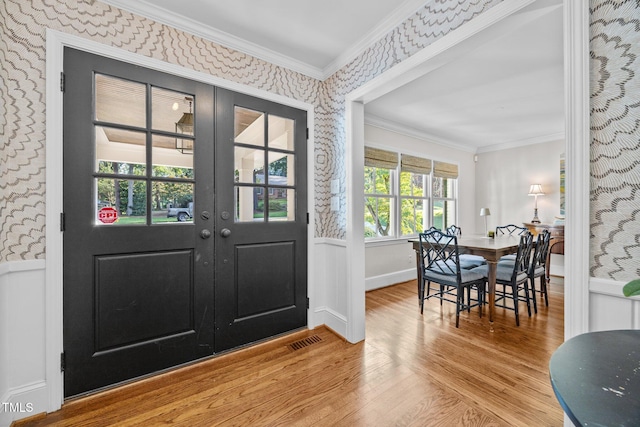 227 W Drewry Ln, Raleigh, NC 27609 - entrance foyer featuring wallpapered walls, wood finished floors, crown molding, a wainscoted wall, and french doors