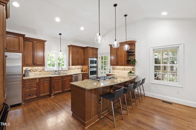 2707 Anderson Dr, Raleigh, NC 27608 - kitchen featuring stainless steel appliances, open shelves, brown cabinets, a kitchen breakfast bar, and lofted ceiling