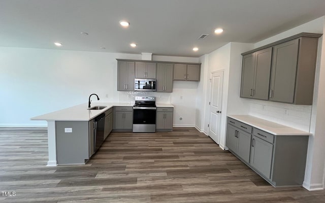 1559 Wendell Valley Blvd, Wendell, NC 27591 - kitchen with appliances with stainless steel finishes, gray cabinets, a peninsula, dark wood-style flooring, and backsplash