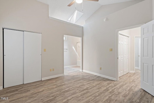 108 Ellsworth Pl, Cary, NC 27511 - unfurnished bedroom with high vaulted ceiling, a skylight, light wood-type flooring, connected bathroom, and ceiling fan