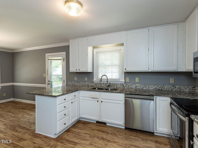 6020 Wildorlyn Cir, Raleigh, NC 27603 - kitchen featuring stainless steel appliances, a peninsula, white cabinets, dark stone countertops, and ornamental molding