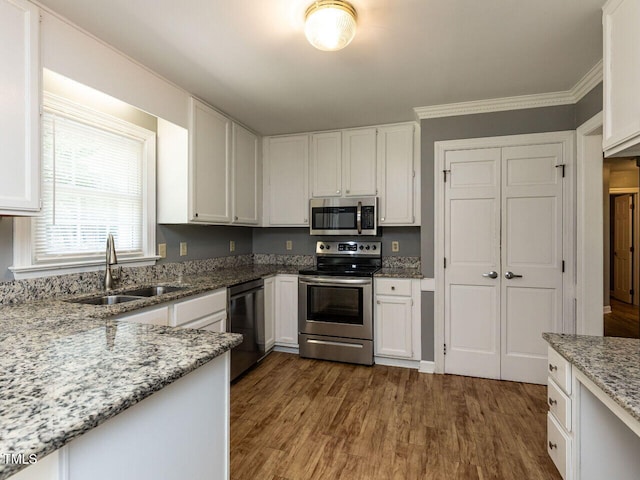 6020 Wildorlyn Cir, Raleigh, NC 27603 - kitchen featuring appliances with stainless steel finishes, dark wood-style flooring, white cabinets, light stone counters, and crown molding