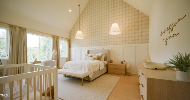 1620 Hunting Ridge Rd, Raleigh, NC 27615 - bedroom featuring wallpapered walls, a decorative wall, multiple windows, wainscoting, and light wood-style floors