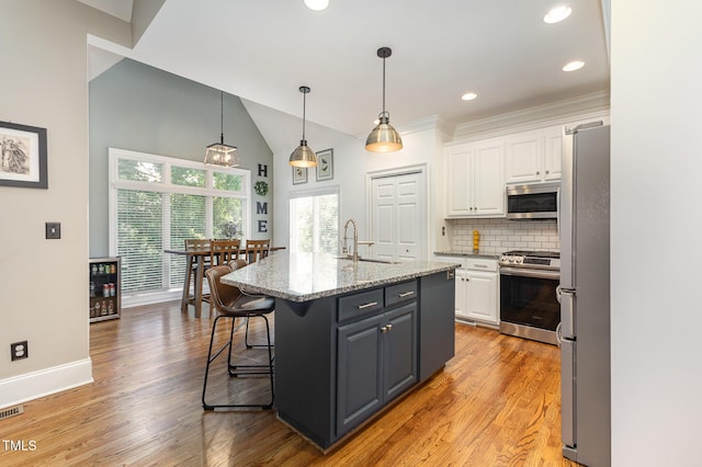 254 Charter Ct SE, Concord, NC 28025 - kitchen featuring stainless steel appliances, white cabinetry, tasteful backsplash, light wood-style floors, and a breakfast bar area