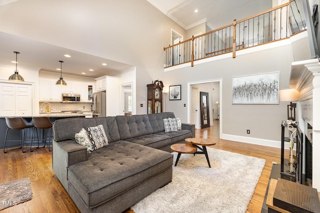 254 Charter Ct SE, Concord, NC 28025 - living area with a fireplace, ornamental molding, light wood-style flooring, a towering ceiling, and recessed lighting
