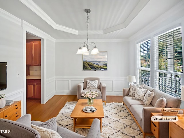 2408 Tiltonshire Ln, Apex, NC 27539 - living room featuring a raised ceiling, a chandelier, wood finished floors, wainscoting, and crown molding