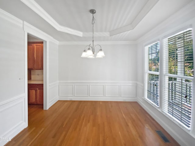 2408 Tiltonshire Ln, Apex, NC 27539 - unfurnished dining area featuring a raised ceiling, a chandelier, light wood-type flooring, a wainscoted wall, and a decorative wall