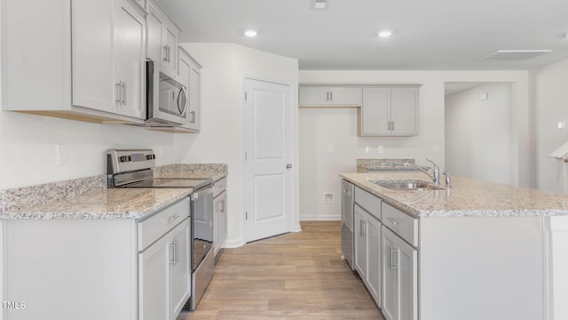 120 Leven Dr, Gibsonville, NC 27249 - kitchen with stainless steel appliances, light wood-style flooring, a center island with sink, light stone counters, and recessed lighting