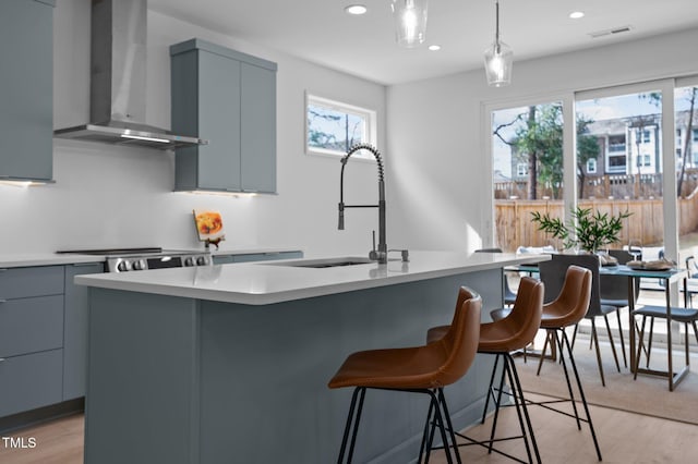 505 Colleton Rd, Raleigh, NC 27610 - kitchen with wall chimney range hood, gray cabinetry, modern cabinets, light countertops, and hanging light fixtures