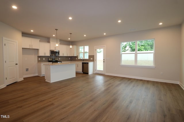 912 Montague Ave, Durham, NC 27703 - kitchen featuring stainless steel appliances, a kitchen island, white cabinets, dark wood-style floors, and tasteful backsplash