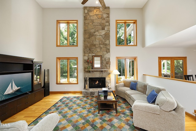 267 Bald Eagle Dr, Pittsboro, NC 27312 - living room featuring light wood-type flooring, a high ceiling, a stone fireplace, and a ceiling fan