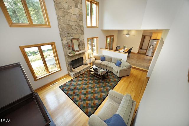 267 Bald Eagle Dr, Pittsboro, NC 27312 - living room with wood finished floors, a high ceiling, a stone fireplace, and a ceiling fan