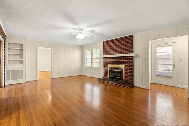 1905 N Rowland Ave N, Lumberton, NC 28358 - unfurnished living room with a ceiling fan, wood finished floors, a textured ceiling, built in features, and a fireplace