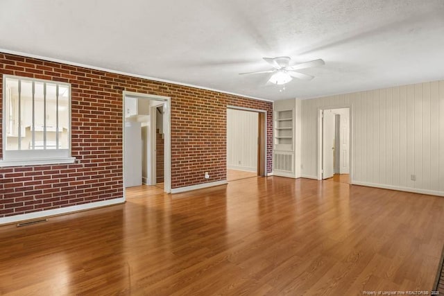 1905 N Rowland Ave N, Lumberton, NC 28358 - empty room with a ceiling fan, brick wall, wood finished floors, and a textured ceiling