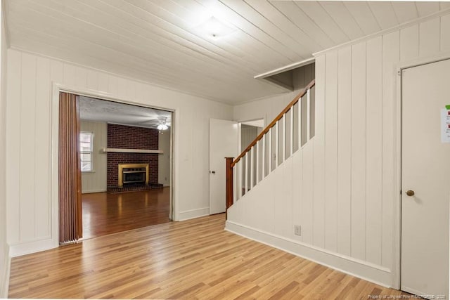 1905 N Rowland Ave N, Lumberton, NC 28358 - empty room featuring light wood finished floors, stairs, a fireplace, and a decorative wall