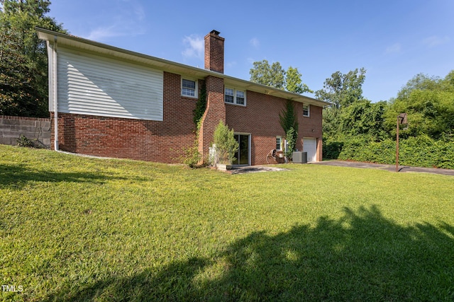 3603 Grimes Ave, Durham, NC 27703 - back of house featuring a chimney, brick siding, a garage, asphalt driveway, and a yard