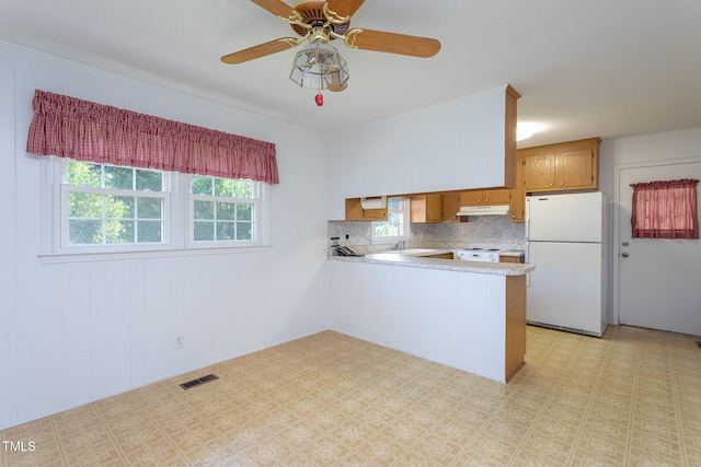 3603 Grimes Ave, Durham, NC 27703 - kitchen featuring white appliances, under cabinet range hood, a peninsula, light countertops, and backsplash