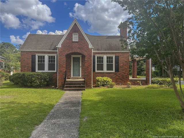 202 E 17th St, Lumberton, NC 28358 - tudor-style house with brick siding, a chimney, a front lawn, and a shingled roof