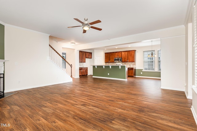 713 Summer Music Ln, Raleigh, NC 27603 - unfurnished living room featuring ceiling fan, dark wood-type flooring, stairway, ornamental molding, and a chandelier