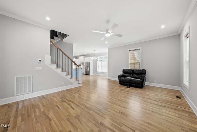 733 Daniel Ridge Rd, Wendell, NC 27591 - unfurnished living room with ornamental molding, stairs, ceiling fan, light wood-type flooring, and a chandelier