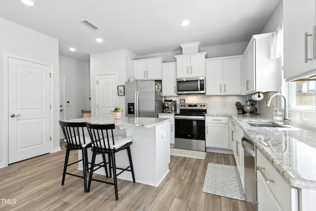 444 Campbell Ridge Pl, Wendell, NC 27591 - kitchen with appliances with stainless steel finishes, a kitchen island, light wood finished floors, white cabinetry, and recessed lighting