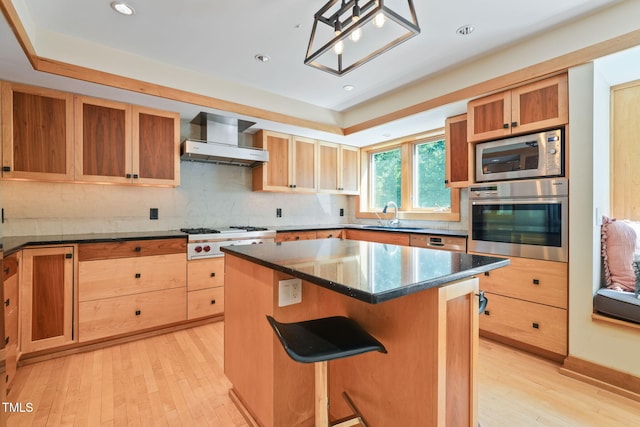 1209 Ravens Point Cir, Raleigh, NC 27614 - kitchen featuring appliances with stainless steel finishes, wall chimney exhaust hood, a center island, light wood-style flooring, and a kitchen bar