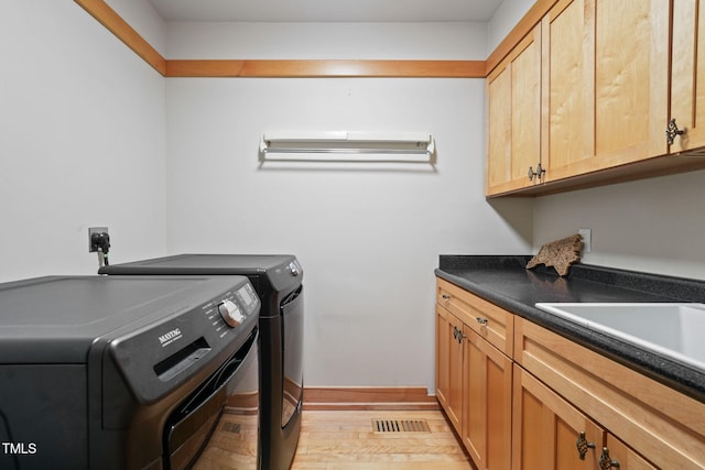 1209 Ravens Point Cir, Raleigh, NC 27614 - washroom featuring washing machine and dryer, cabinet space, and light wood-type flooring