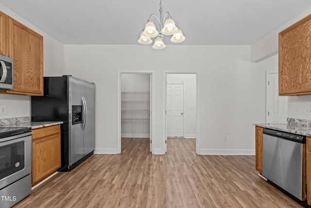 4716 Miller Dr, Durham, NC 27704 - kitchen with stainless steel appliances, a chandelier, light wood-style floors, brown cabinetry, and light stone counters