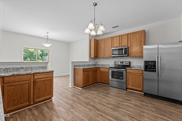 4716 Miller Dr, Durham, NC 27704 - kitchen featuring stainless steel appliances, dark wood-style flooring, brown cabinetry, and light stone counters