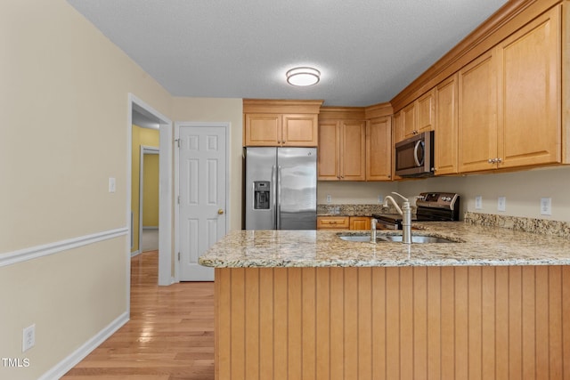 276 Sagamore Dr, Louisburg, NC 27549 - kitchen featuring appliances with stainless steel finishes, a peninsula, light wood-type flooring, light stone countertops, and a textured ceiling