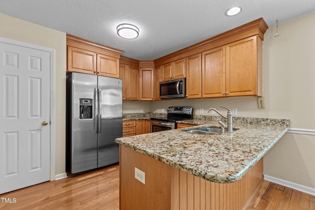 276 Sagamore Dr, Louisburg, NC 27549 - kitchen with stainless steel appliances, a peninsula, light wood-style flooring, light stone counters, and brown cabinetry