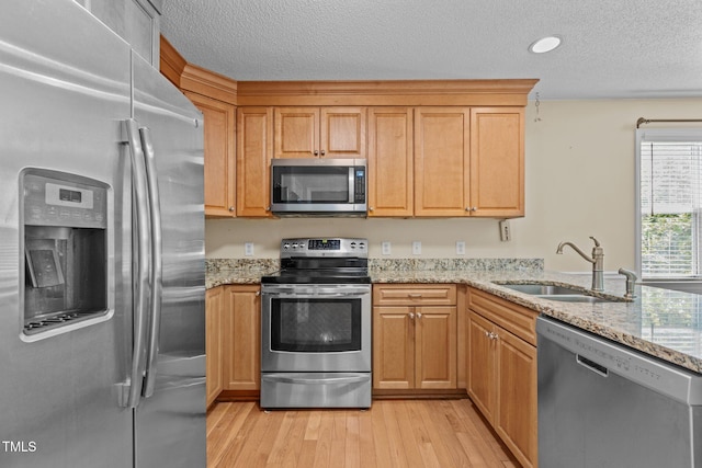 276 Sagamore Dr, Louisburg, NC 27549 - kitchen with appliances with stainless steel finishes, light wood finished floors, light stone counters, and a textured ceiling