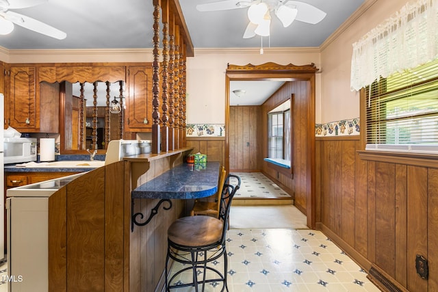 1315 Elder Way, Burlington, NC 27215 - kitchen featuring ceiling fan, wooden walls, white microwave, wainscoting, and brown cabinets