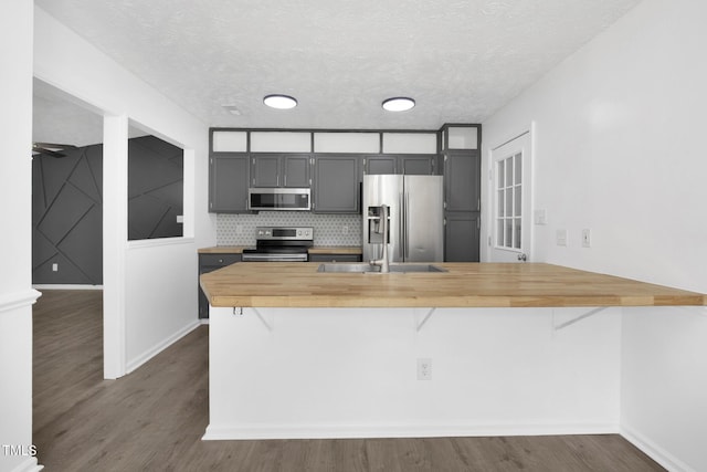 153 Eulon Loop, Raeford, NC 28376 - kitchen with appliances with stainless steel finishes, wood counters, a peninsula, a breakfast bar area, and dark wood finished floors