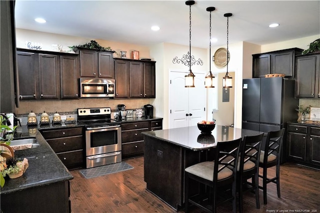 930 Old Vander Rd, Fayetteville, NC 28312 - kitchen featuring appliances with stainless steel finishes, dark wood finished floors, tasteful backsplash, dark brown cabinets, and decorative light fixtures