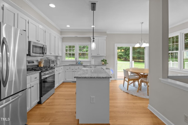 10721 Marabou Ct, Raleigh, NC 27614 - kitchen featuring stainless steel appliances, crown molding, white cabinetry, a kitchen island, and light wood-style floors
