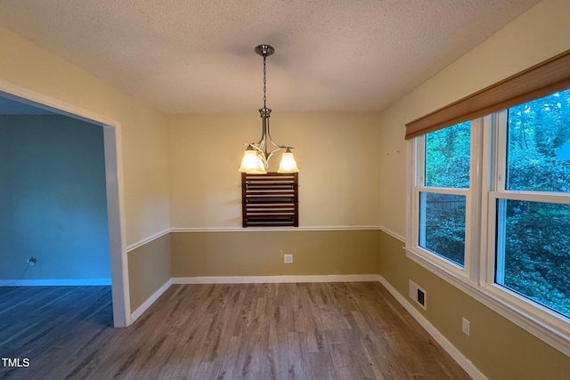 609 Sloan Dr, Cary, NC 27511 - spare room featuring a textured ceiling, wood finished floors, and a chandelier