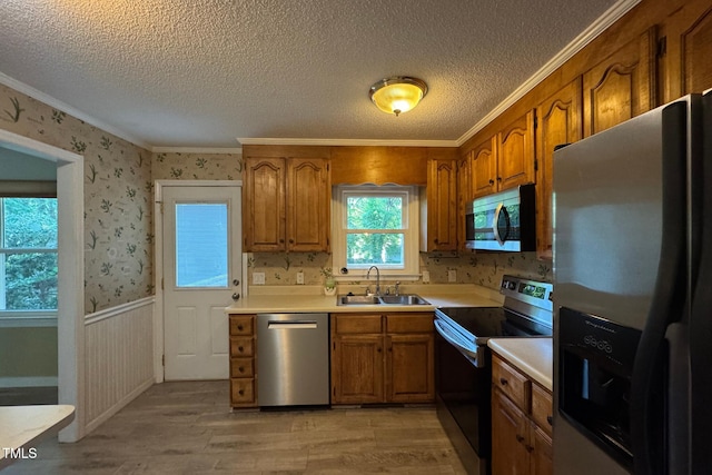 609 Sloan Dr, Cary, NC 27511 - kitchen with appliances with stainless steel finishes, brown cabinets, light wood-style floors, crown molding, and a textured ceiling