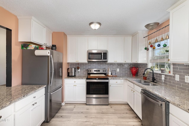 11 Sherman Rd, Fuquay Varina, NC 27526 - kitchen with stainless steel appliances, light wood finished floors, backsplash, white cabinetry, and a textured ceiling