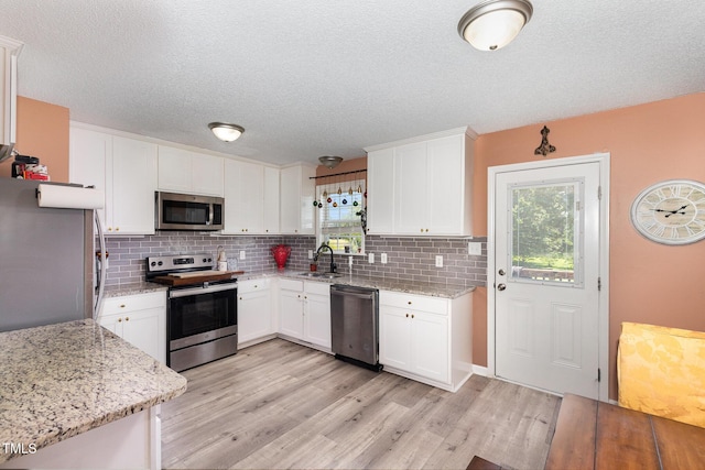 11 Sherman Rd, Fuquay Varina, NC 27526 - kitchen featuring appliances with stainless steel finishes, tasteful backsplash, light wood finished floors, white cabinetry, and light stone countertops