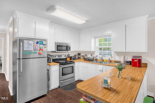 117 James Dr, Pine Level, NC 27568 - kitchen featuring appliances with stainless steel finishes, crown molding, dark wood-style floors, white cabinets, and a peninsula