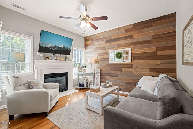 8221 Hempshire Pl Unit 101, Raleigh, NC 27613 - living room with plenty of natural light, wooden walls, ceiling fan, an accent wall, and a glass covered fireplace
