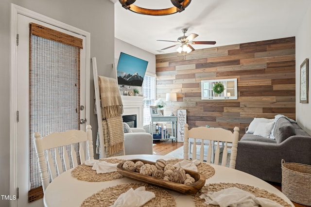 8221 Hempshire Pl Unit 101, Raleigh, NC 27613 - dining space with a ceiling fan, wooden walls, a glass covered fireplace, and wood finished floors