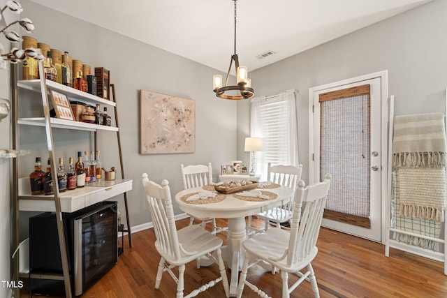 8221 Hempshire Pl Unit 101, Raleigh, NC 27613 - dining space with a chandelier, wood finished floors, a bar, and wine cooler