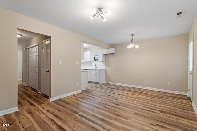 1611 Poole Rd, Raleigh, NC 27610 - unfurnished living room featuring a chandelier and light wood finished floors