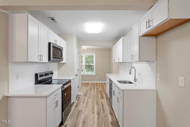 1611 Poole Rd, Raleigh, NC 27610 - kitchen with stainless steel appliances, light wood-style floors, decorative backsplash, and light countertops