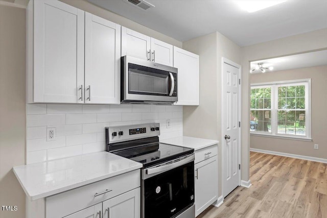 1611 Poole Rd, Raleigh, NC 27610 - kitchen featuring appliances with stainless steel finishes, backsplash, light wood finished floors, and white cabinetry